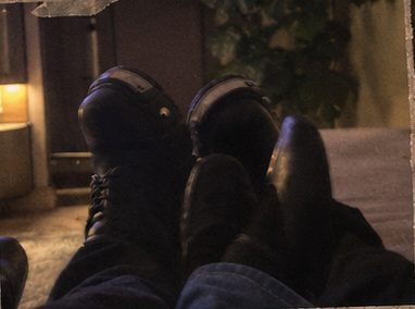 Our shoes side by side, feet up together in a dim room